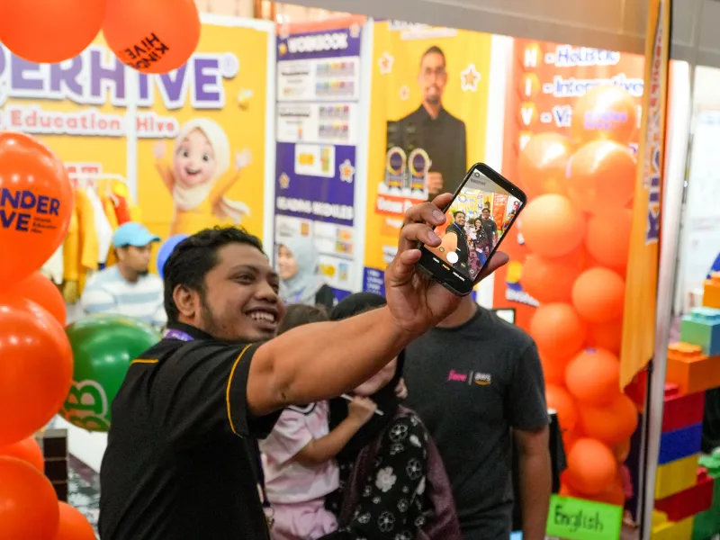 Visitor taking a photo at the KinderHive booth during ECEE 2026