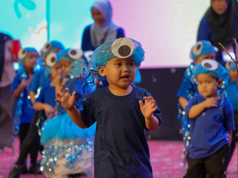 Young KinderHive performer wearing a blue costume during the 2026 Junior Concert