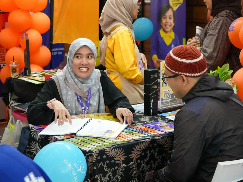 KinderHive team member explaining preschool programmes to a visitor at ECEE 2026